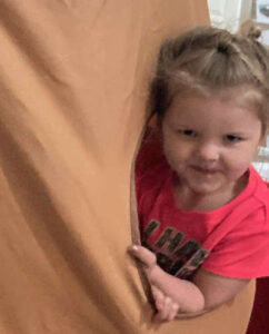 Smiling preschool girl playing in a tree tent at a learning center in Minnesota